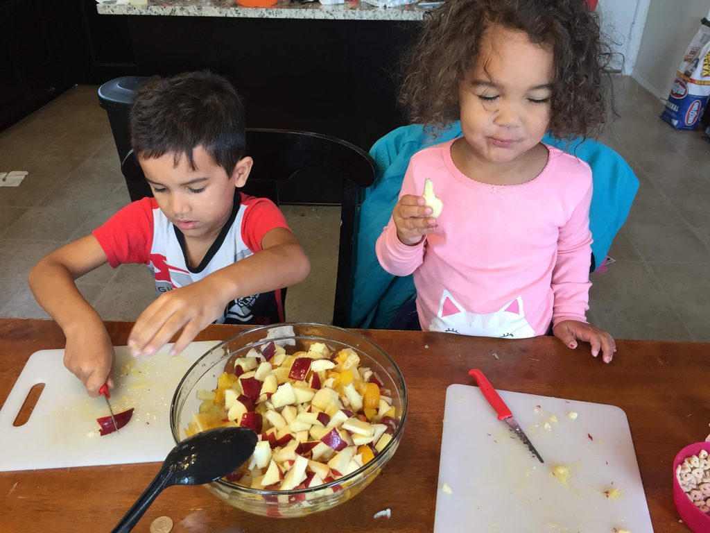Children helping make fruit salad using kid-safe knives and cutting boards.