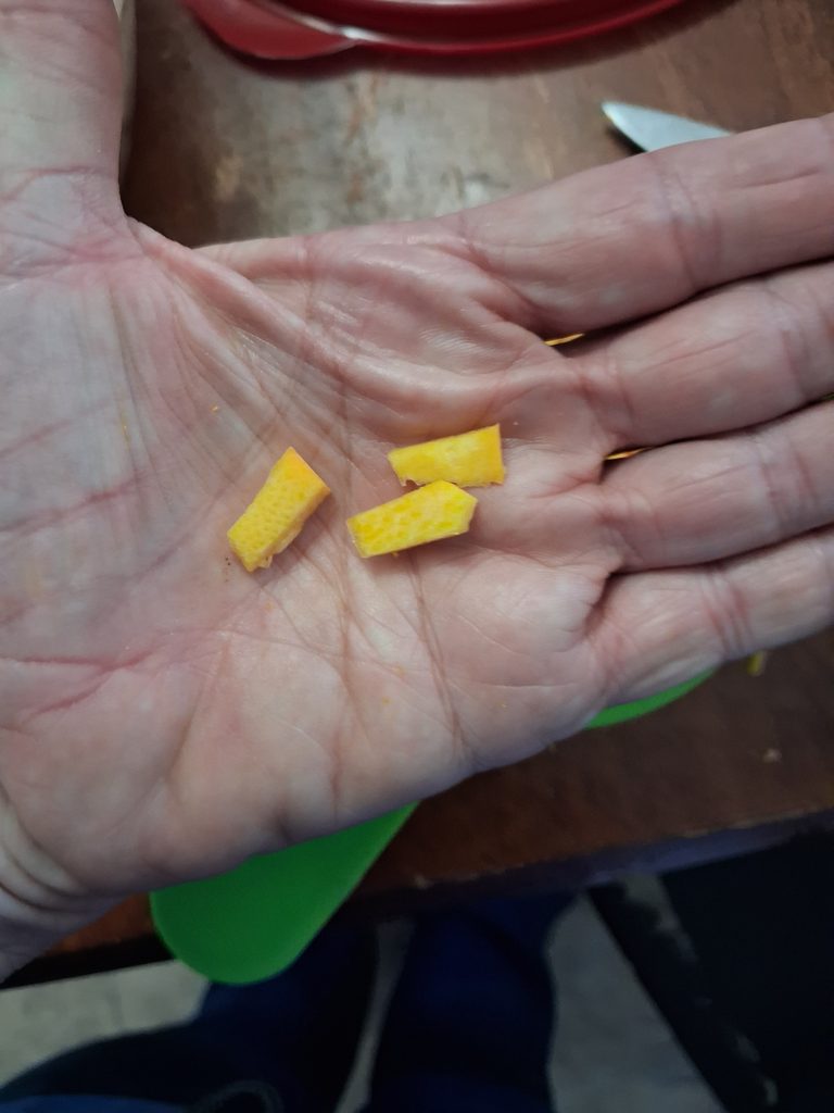 Small pieces of raw pumpkin held in a hand to show the size for Fall Harvest Fruit Salad.